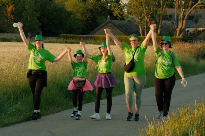 Children and adults walking outside with arms in the air