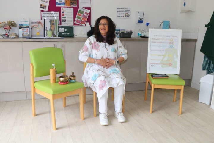 Female sitting on a green chair, wearing white, smiling
