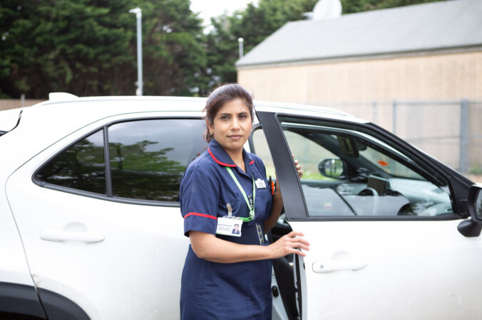 Nurse standing in front of a car
