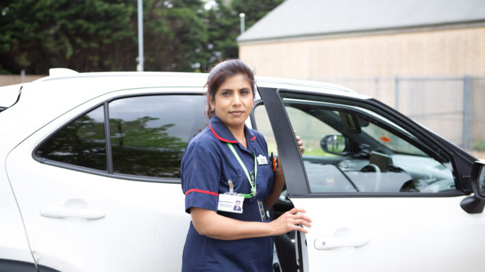 Nurse standing in front of a car