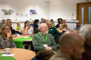 Males and females sitting at tables smiling 
