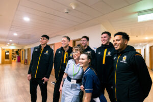 Males in black tracksuits with 2 female nurses