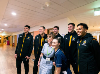 Males in black tracksuits with 2 female nurses