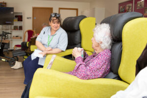 Nurse and female sitting in a chair chatting 