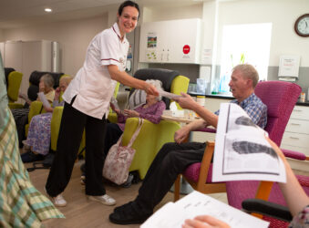 Female wearing white uniform giving out information to people sitting in chairs