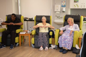 2 females and 1 male exercising in chairs
