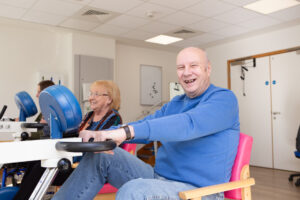 Male in blue jumper sitting on a chair on a bike