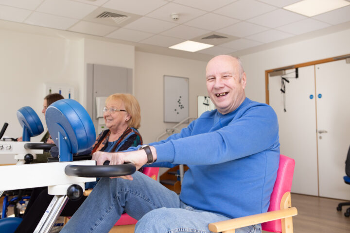 Male in blue jumper sitting on a chair on a bike
