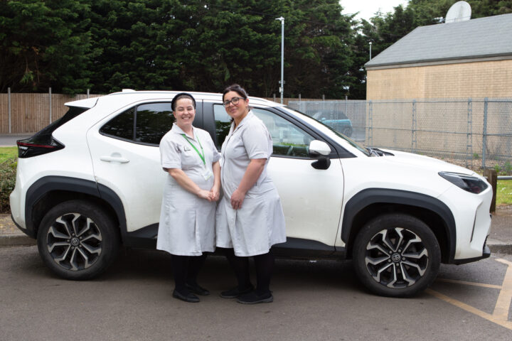 Two Nurses standing in front of a car