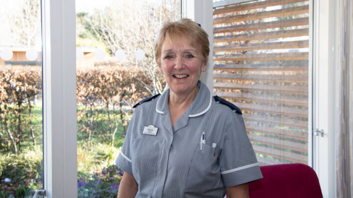 Female in blue nurse uniform smiling at the camera inside