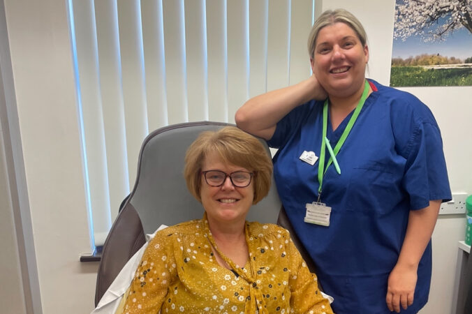 female sitting in a chair and female nurse standing next to her
