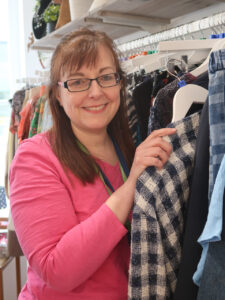 Female holding a jacket, smiling at the camera
