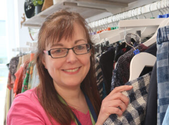 Female holding a jacket, smiling at the camera