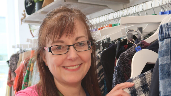 Female holding a jacket, smiling at the camera