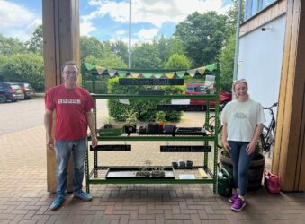 2 males standing in front of a plant stall
