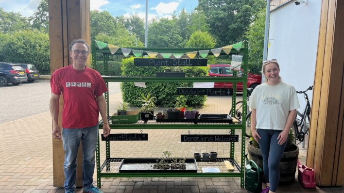 2 males standing in front of a plant stall
