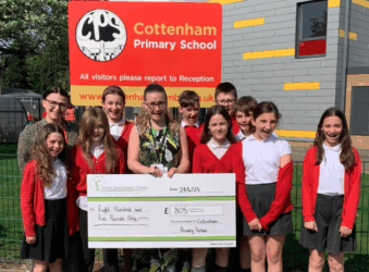 Students in red outside Cottenham Primary school sign