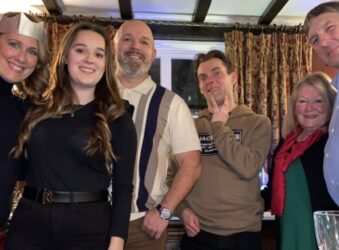 family photo 3 women and three men in a pub looking down at the camera smiling