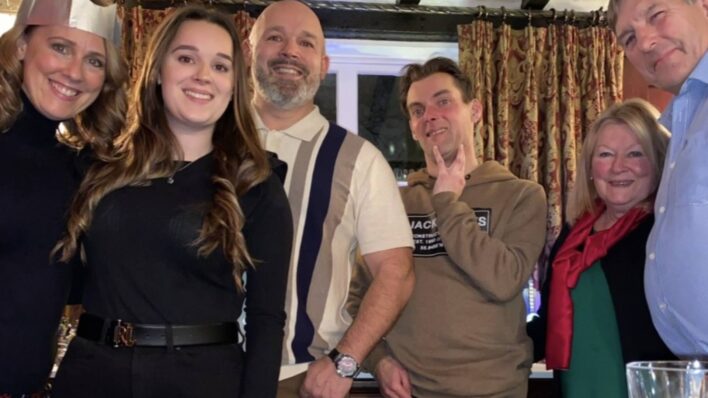 family photo 3 women and three men in a pub looking down at the camera smiling