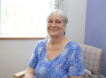 Female sitting in a chair, wearing a blue dress