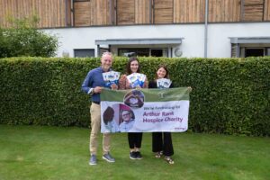 Male and 2 females in the garden holding a sign 