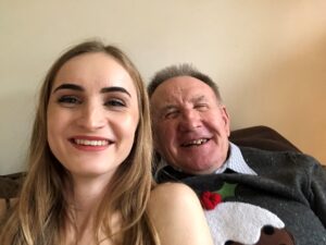 young lady and older man smiling at the camera, head and shoulder in shot