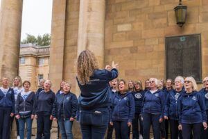 Group of singers wearing blue jackets, singing outside