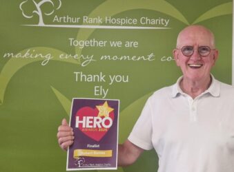 Finalist for Ely Hero Robert Barns holding certificate with green background and white logo
