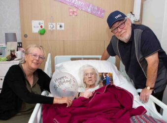 Two adults and a female in a bed