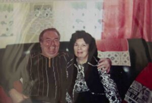 Photo of a male and female on a sofa looking at the camera 