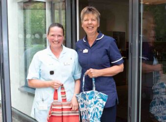 2 females in uniform holding cloth bags