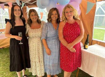 Four females in dresses in a marquee