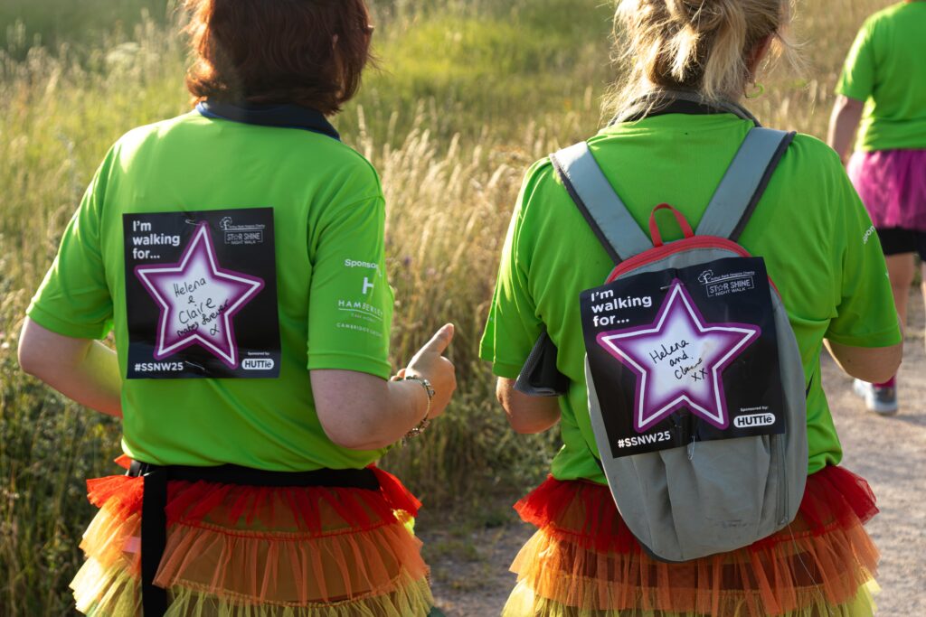 The backs of two women who have a square piece of paper with the messages on for their loved ones.