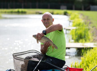 Male in green t-shirt holding a fish outside
