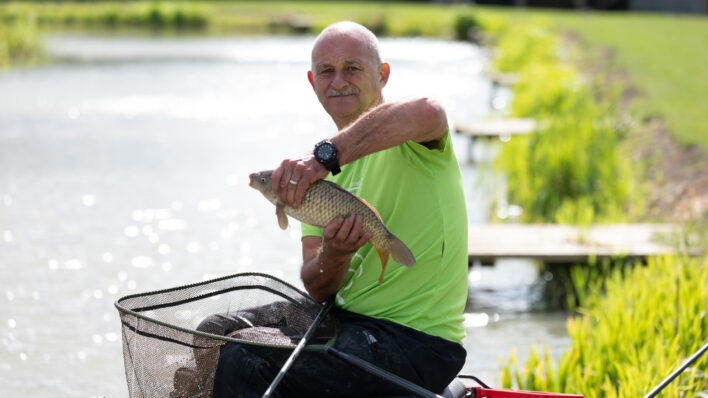 Male in green t-shirt holding a fish outside