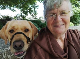Lady smiling at camera with golden Labrador dog