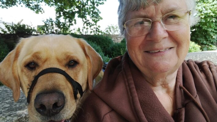 Lady smiling at camera with golden Labrador dog