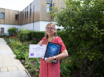 Female holding awards outside a large building