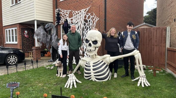 Large toy skeleton outside a house with people
