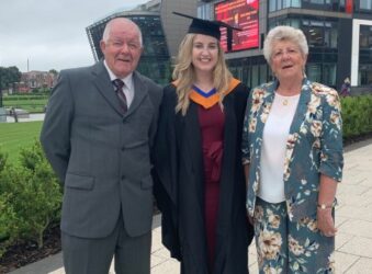 Male and 2 females. One wearing graduation gown and hat