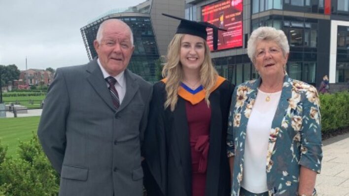 Male and 2 females. One wearing graduation gown and hat