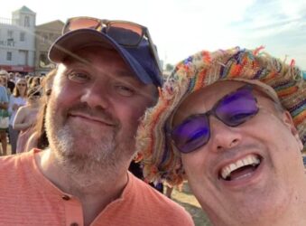 two males wearing hats, smiling at the camera