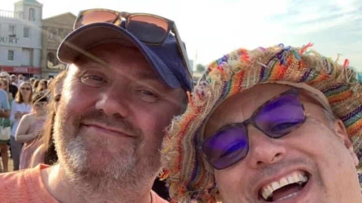 two males wearing hats, smiling at the camera