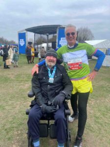 Male in green running gear and a man in a wheelchair