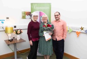 2 female and a male with certificate and flowers