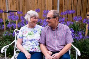 Female and male sitting on a bench smiling at each other