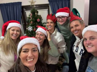 Group of adults wearing red Santa hats