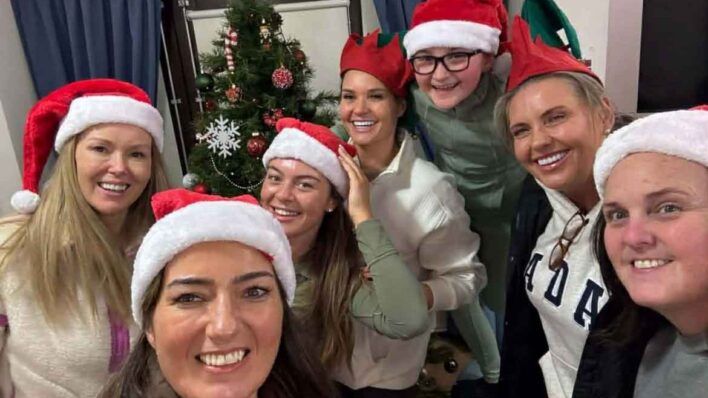 Group of adults wearing red Santa hats