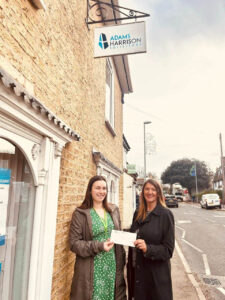 2 females outside a building with a cheque