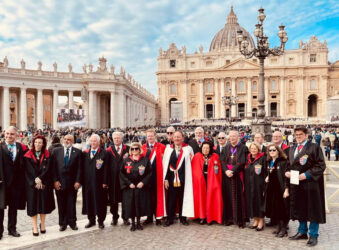 Group of adults dressed in red and black outside large building